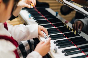 東京ルクスピアノ教室の無料体験レッスン風景 子どもと講師がグランドピアノでドの音に人形を置いている様子｜東京のピアノ教室 東京ルクスピアノ教室